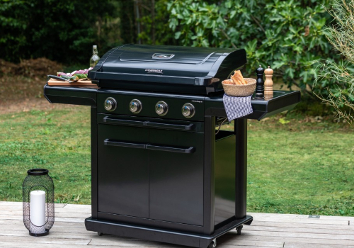 Barbecue gaz onyx noir sur terrasse de jardin avec reposes plats, moulin à poivre et sel